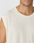 Close-up of a man wearing a sleeveless crew-neck t-shirt in a light cream or off-white color, showing the fabric texture and fit.