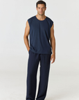 A man modeling a dark navy blue sleeveless top and matching navy blue pants against a plain light gray studio background.