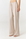 A model wearing light beige wide-leg drawstring pants and white slide sandals, shown from the waist down against a plain white studio background.