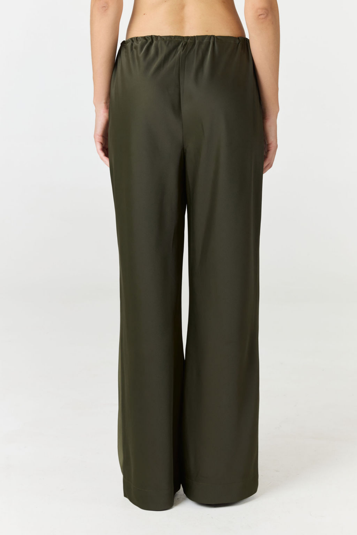 A model shown from the back wearing dark olive green wide-leg pants against a plain white studio background.