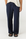A person wearing dark navy wide-leg drawstring pants with a cream-colored top and black slide sandals, shown from the waist down against a plain light background.