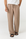 A person wearing loose, wide-leg taupe pants with a drawstring waist, paired with a white top and black sandals, shown from the waist down against a plain light background.