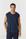 A man wearing a sleeveless navy blue t-shirt and matching navy pants, standing against a light gray studio background.