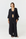 A woman modeling a black open-front kimono-style cardigan over a black crop top and wide-leg pants, photographed against a clean light gray studio background.