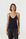 A woman modeling a black spaghetti-strap camisole tank top paired with black satin pants against a plain white studio background.