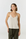 A woman modeling a light beige spaghetti-strap camisole top paired with dark olive green drawstring pants, shot against a seamless light gray studio background.